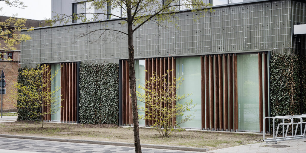 Ground-based green façade created with the MobiClimb system, featuring climbing plants growing from the soil with a robust support structure, providing an instant green and sustainable building exterior.