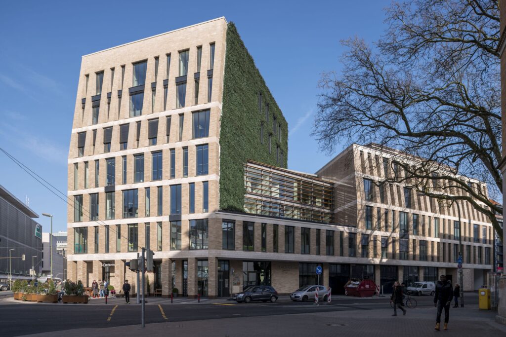 Panoramaaufnahme einer vollständig begrünten Fassade mit integriertem Fensterband, realisiert mit dem Mobilane WallPlanter-System.