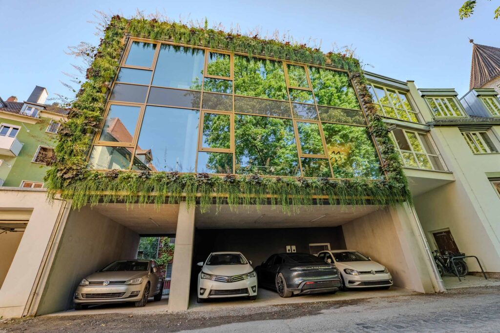 Kantoorgebouw met een volledig omlijste groene glazen gevel boven een carport
